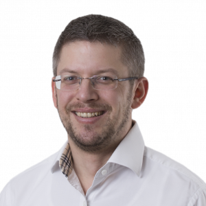 Bild von Steffen Rühl in weißem Hemd, lächelt in die Kamera.